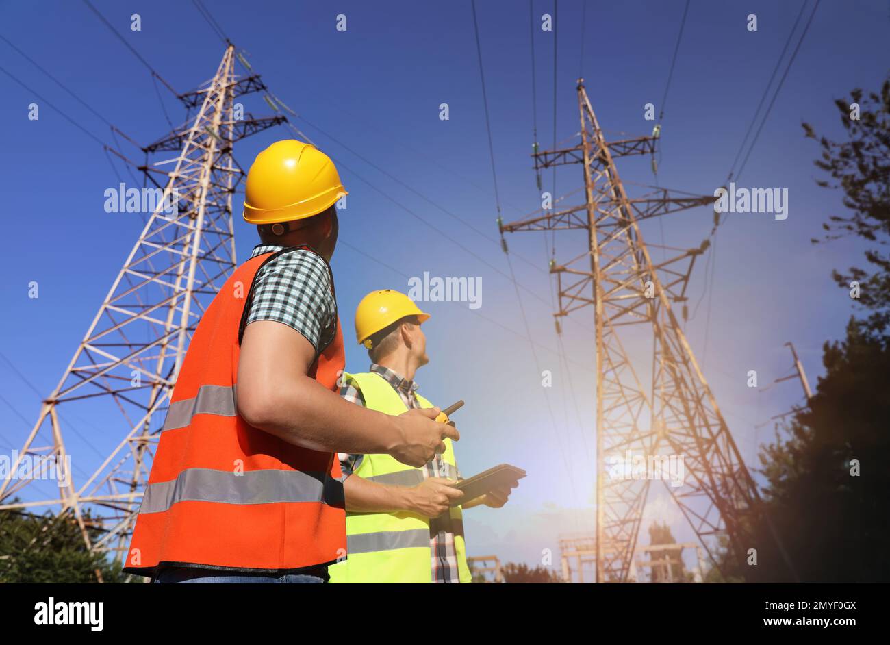 Professional electricians in uniforms near high voltage towers Stock