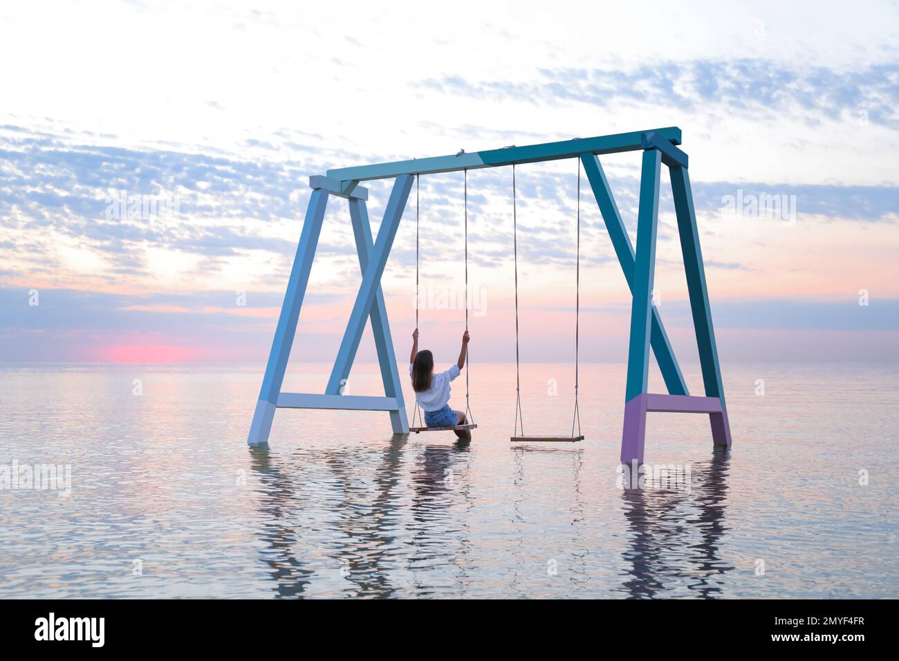 Young woman enjoying sunrise on swing over water Stock Photo Alamy