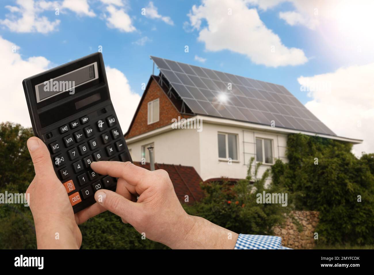 Man using calculator against house with installed solar panels. Renewable  energy and money saving Stock Photo - Alamy