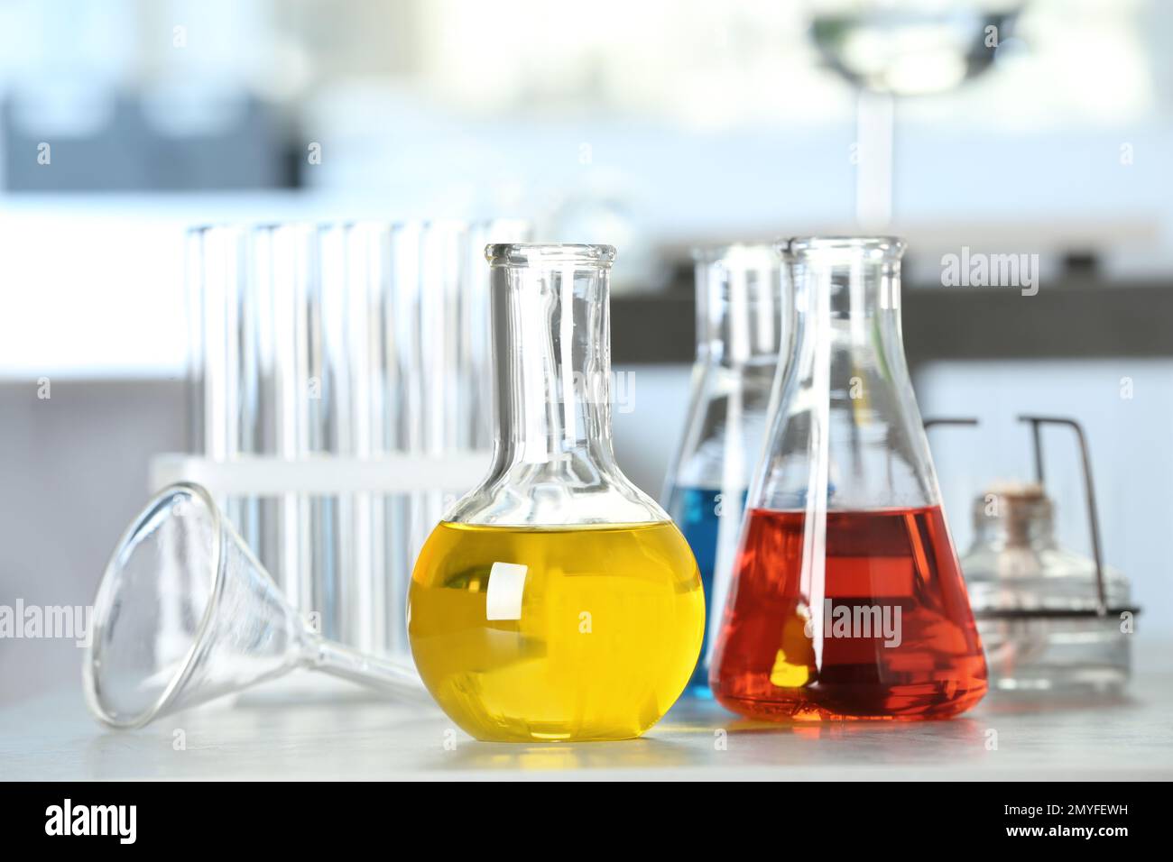 Laboratory glassware with different liquid samples on table Stock Photo