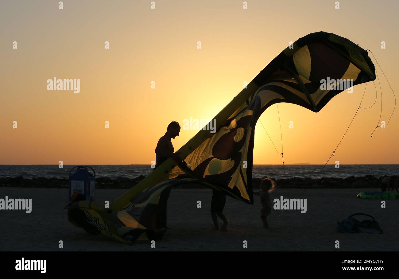 A man and his children bring down their kite surfing sail at Kite Beach