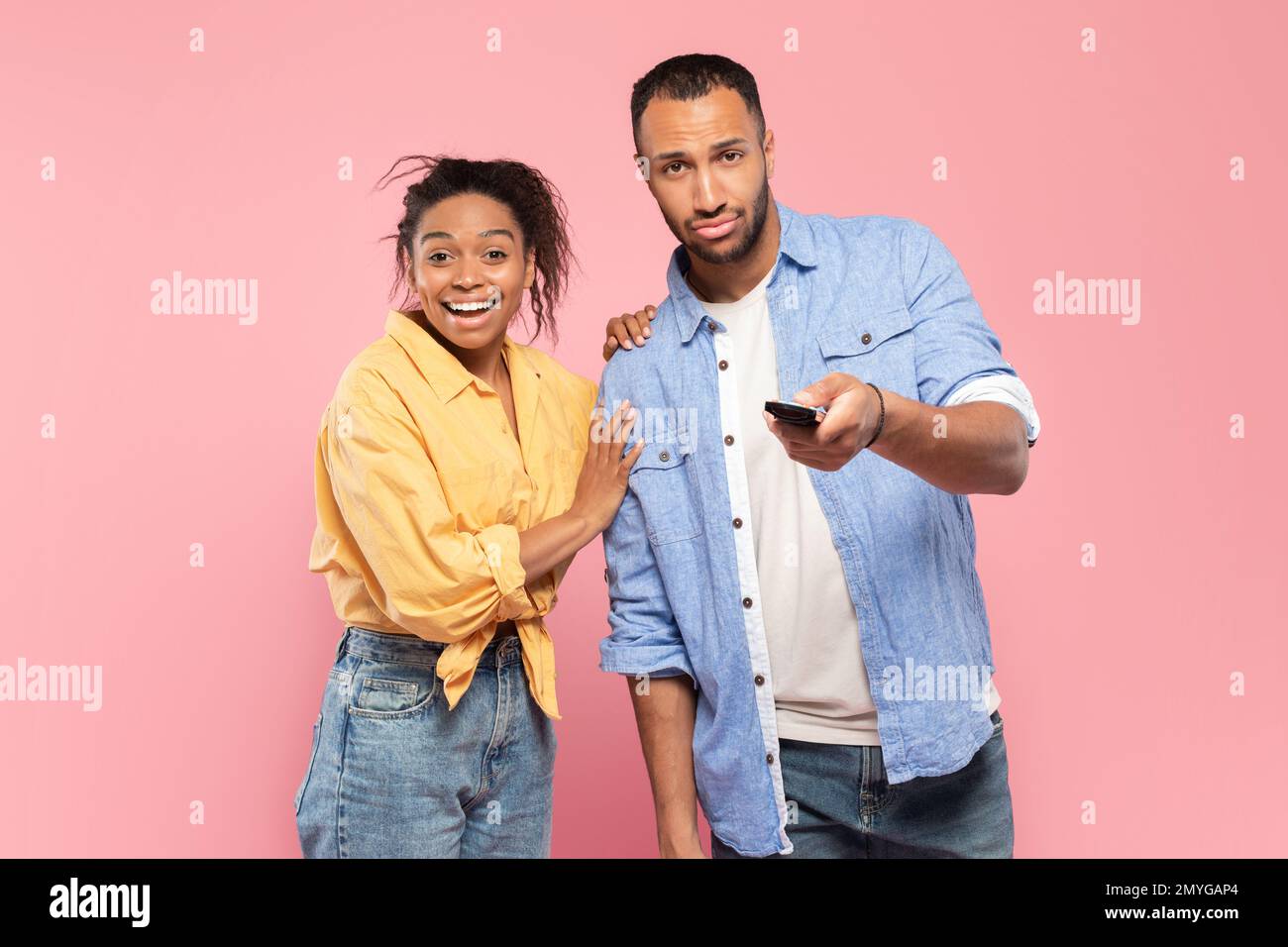 Black couple with remote control watching television program or show on