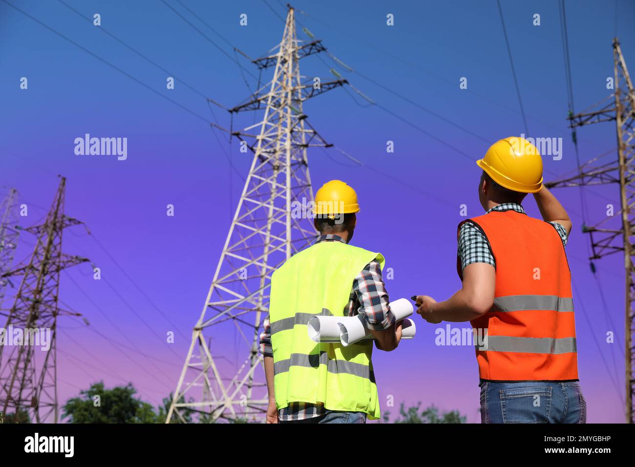 Professional electricians in uniforms near high voltage towers Stock