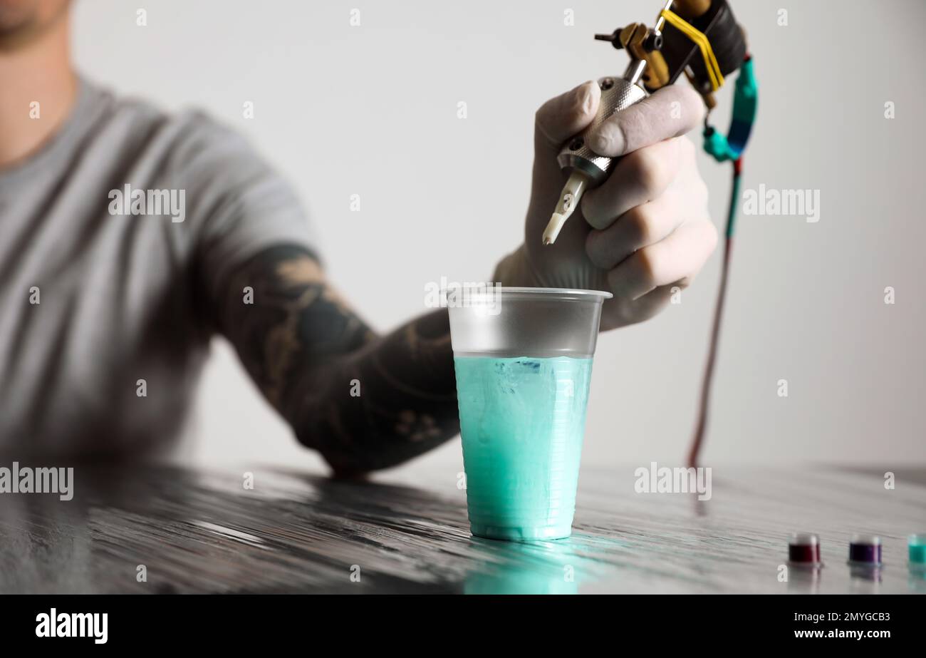 Tattoo artist cleaning machine needle at table, closeup Stock Photo Alamy