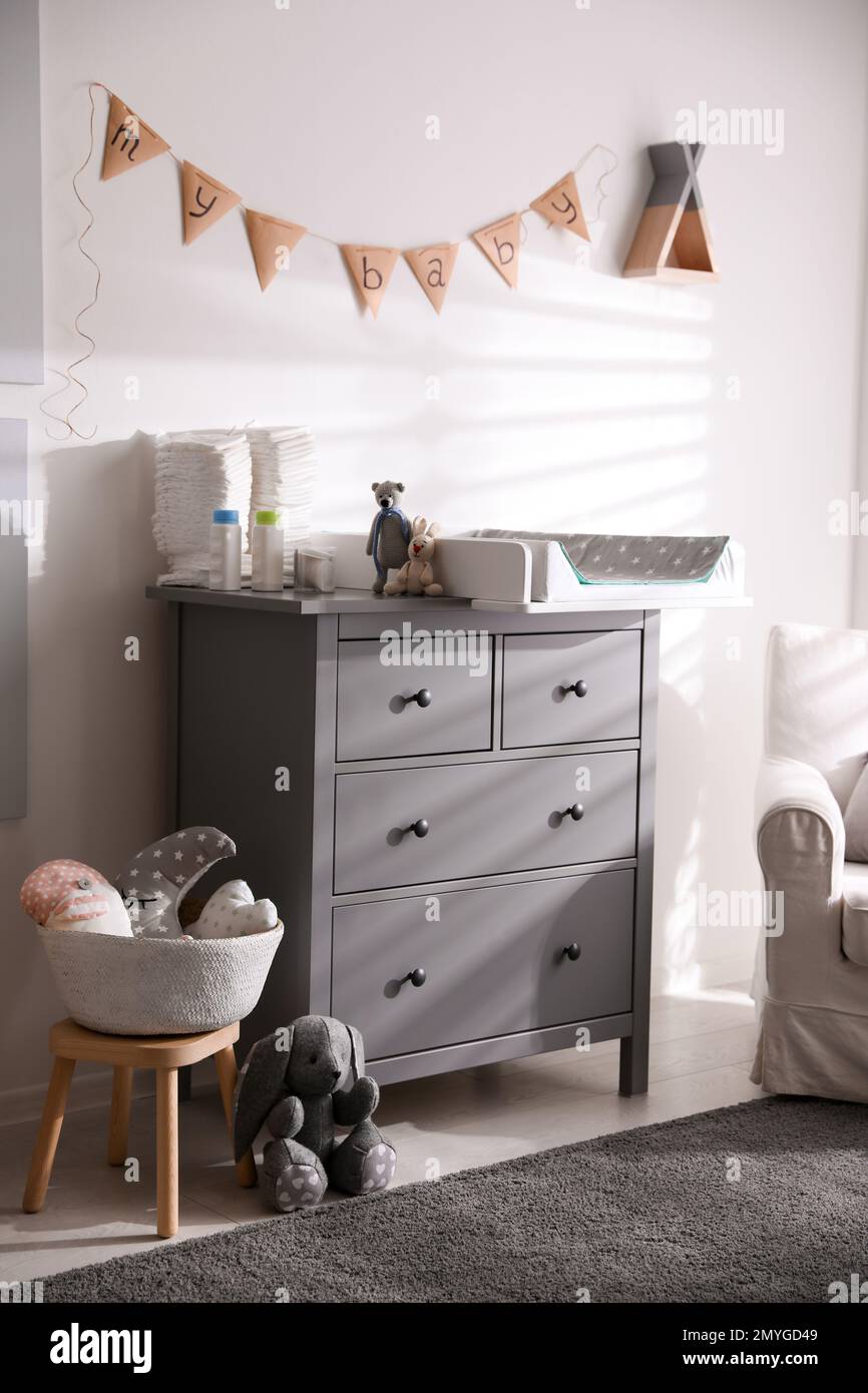 Chest of drawers with changing tray and pad in baby room. Interior