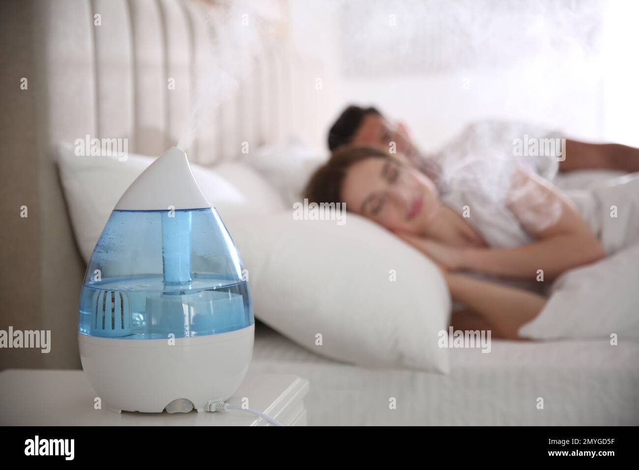 Couple sleeping in bedroom with modern air humidifier Stock Photo Alamy