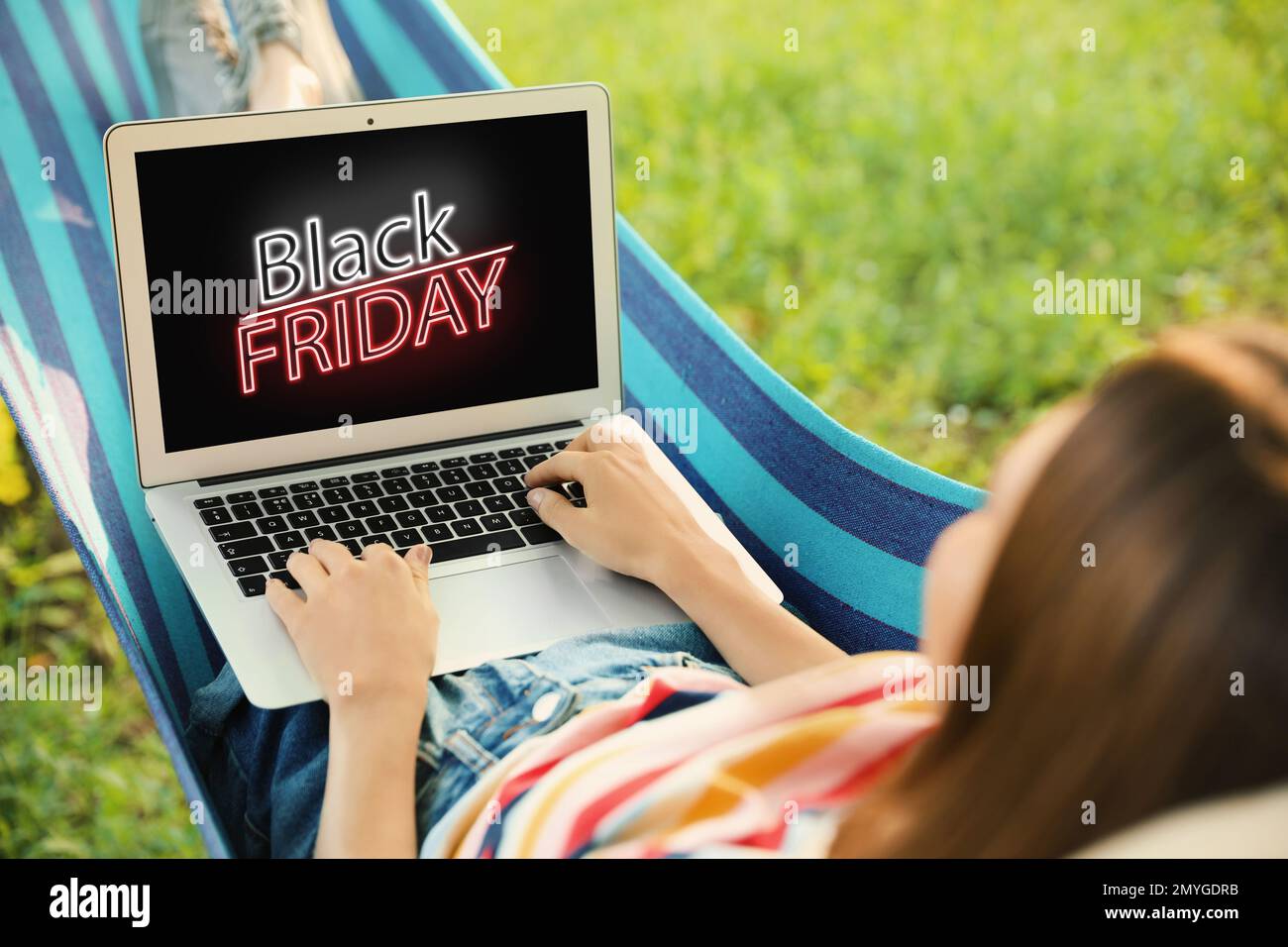 Black Friday. Woman shopping online using laptop in hammock Stock Photo