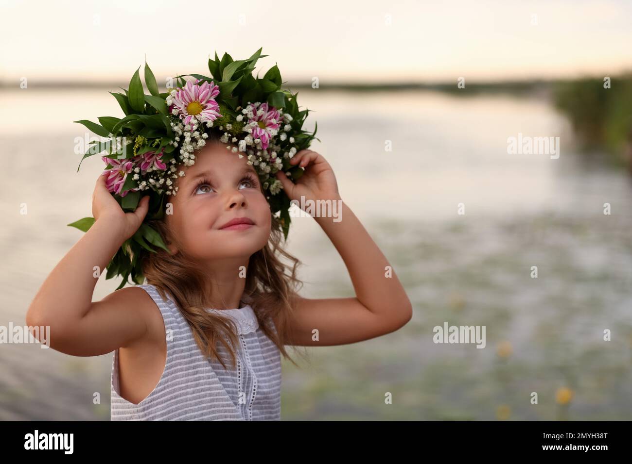Cute little girl wearing wreath made of beautiful flowers near river ...