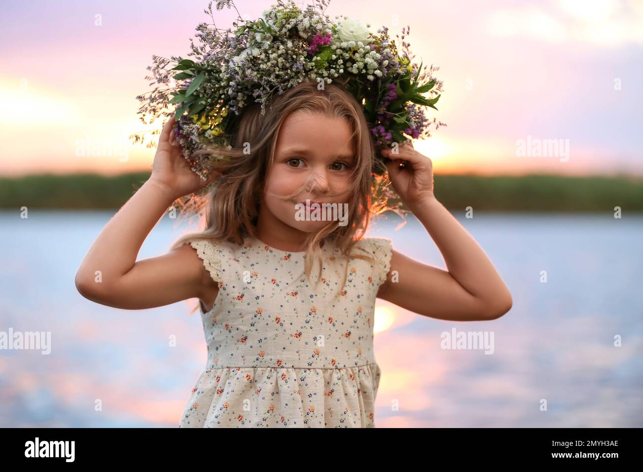 Cute little girl wearing wreath made of beautiful flowers near river at ...