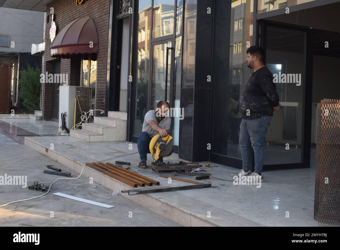 A metal worker and his chop saw cutting metal tubing at a store front in Duhok, Northern Iraq Stock Photo