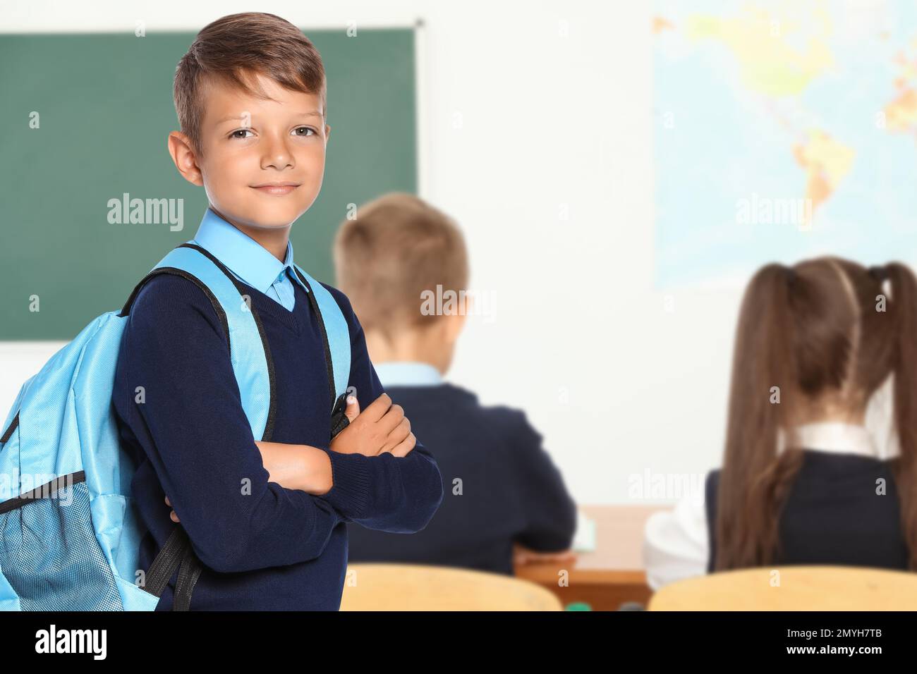 Little boy with backpack in school classroom Stock Photo Alamy