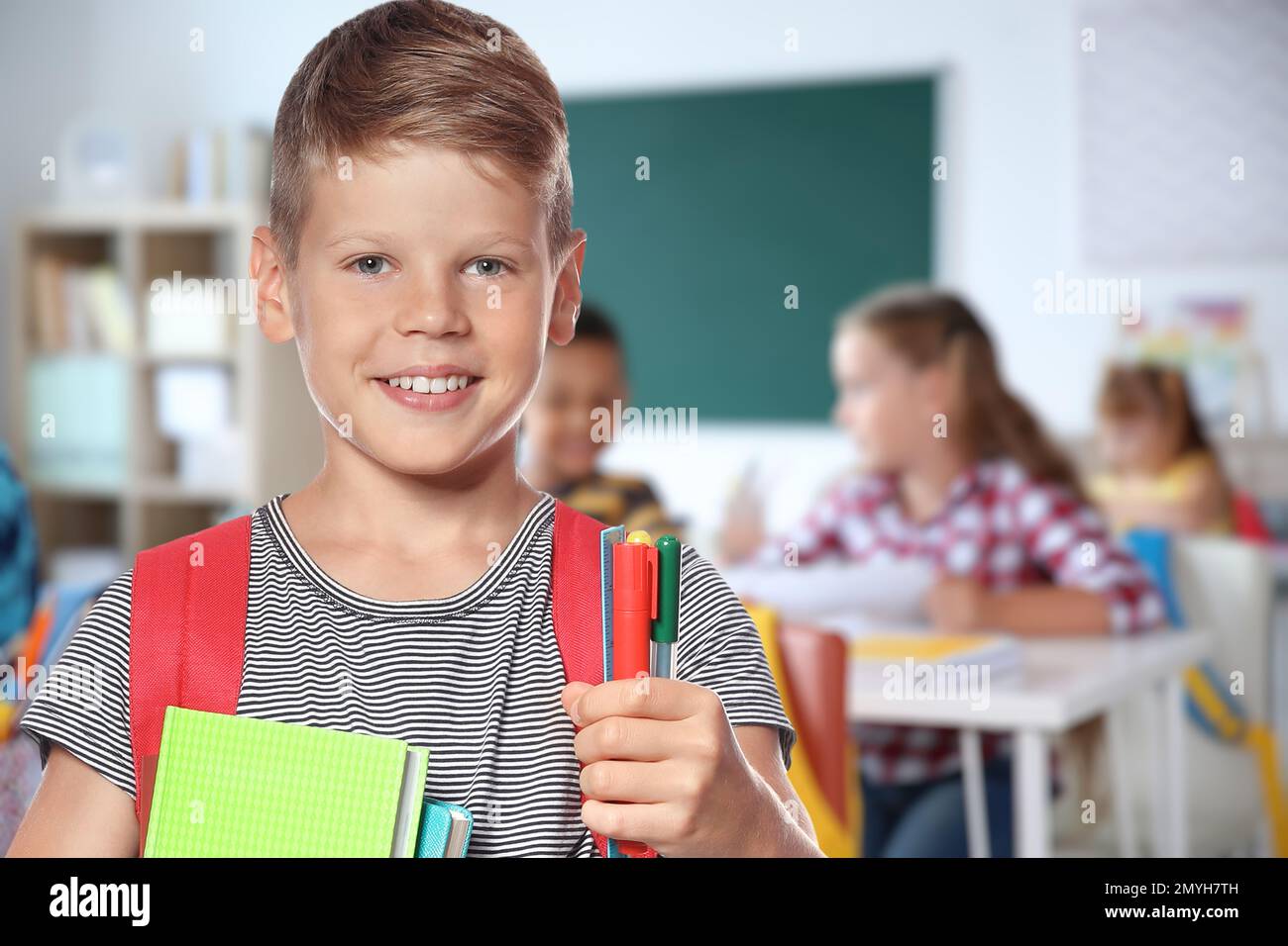Happy boy with backpack in school classroom Stock Photo - Alamy