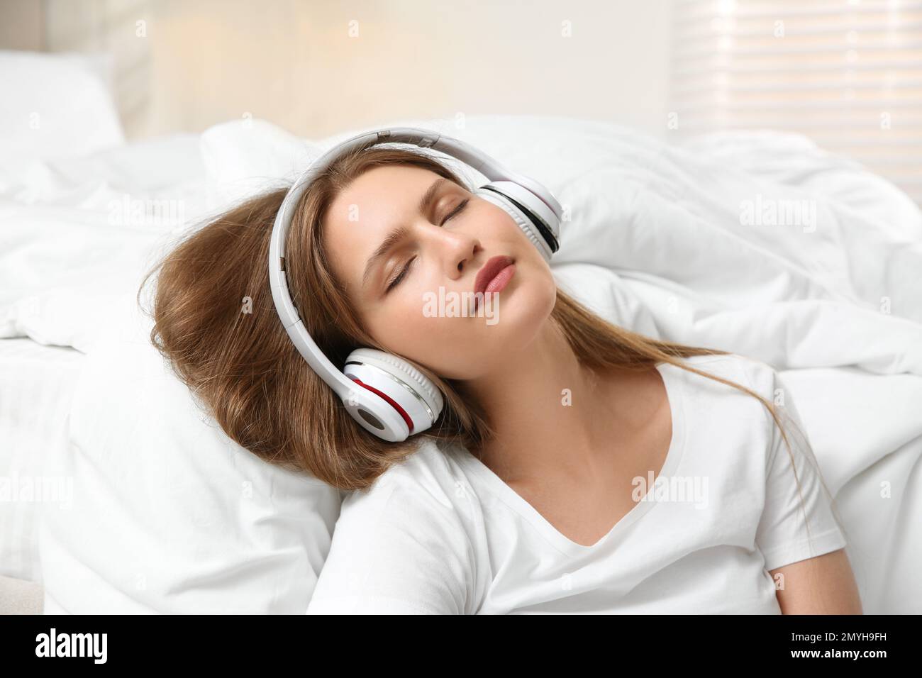 Lazy young woman with headphones sleeping in bedroom Stock Photo Alamy