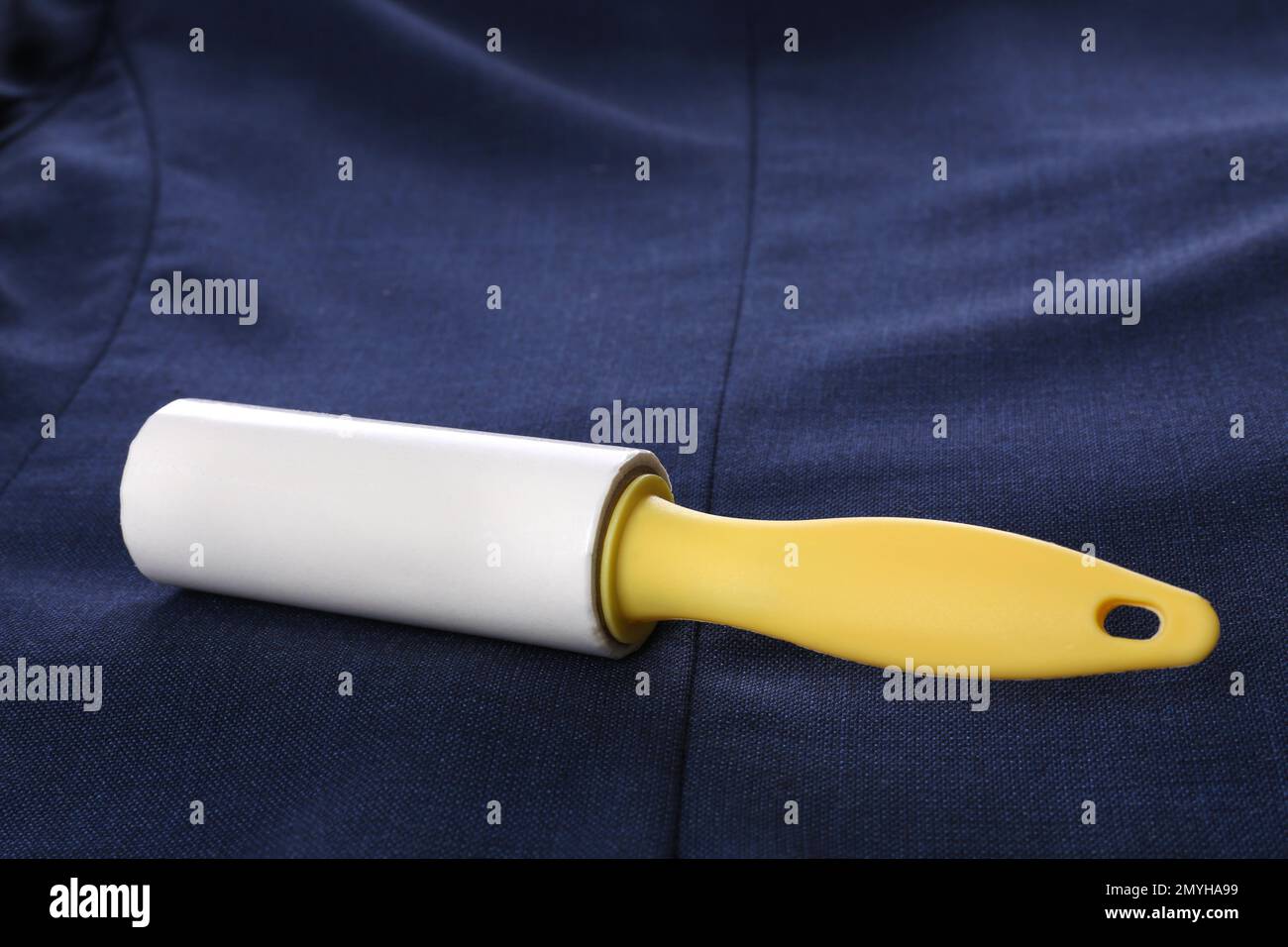 New lint roller with yellow handle on blue jacket Stock Photo