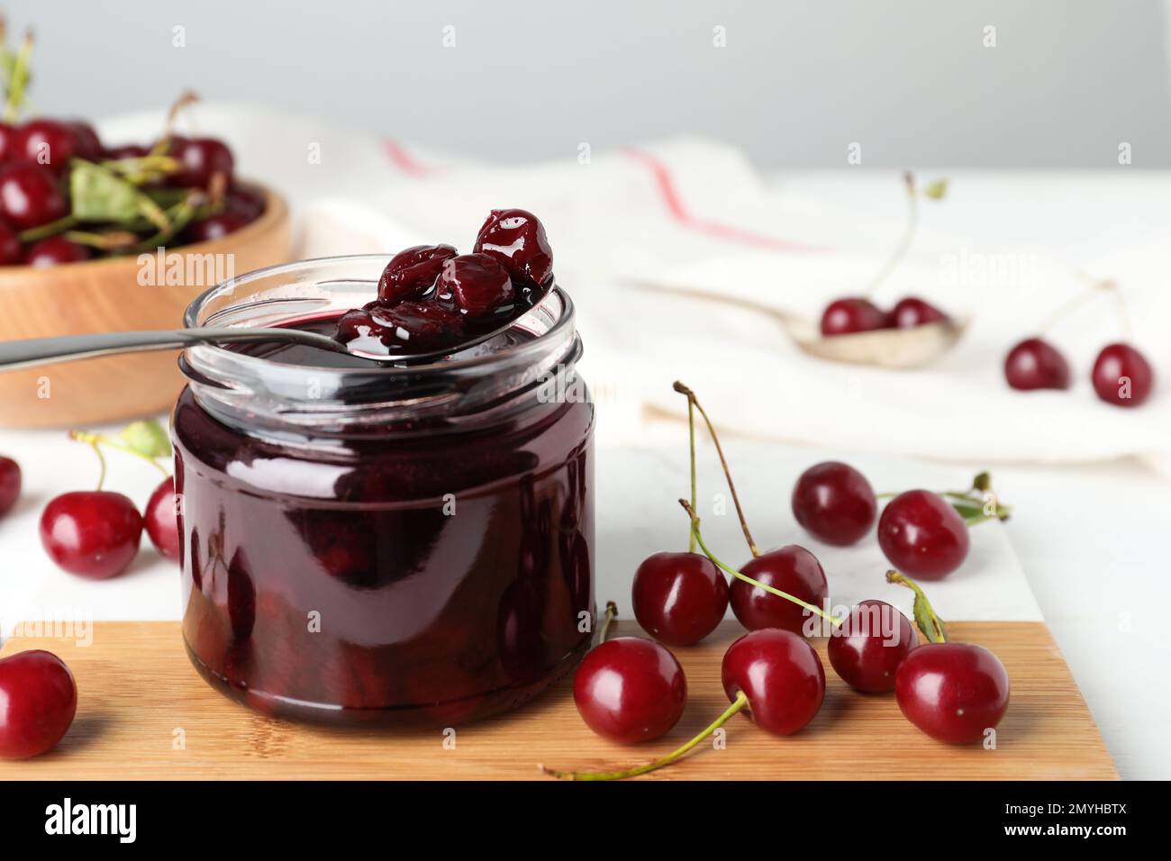 Jar of pickled cherries and fresh fruits on table, closeup Stock Photo