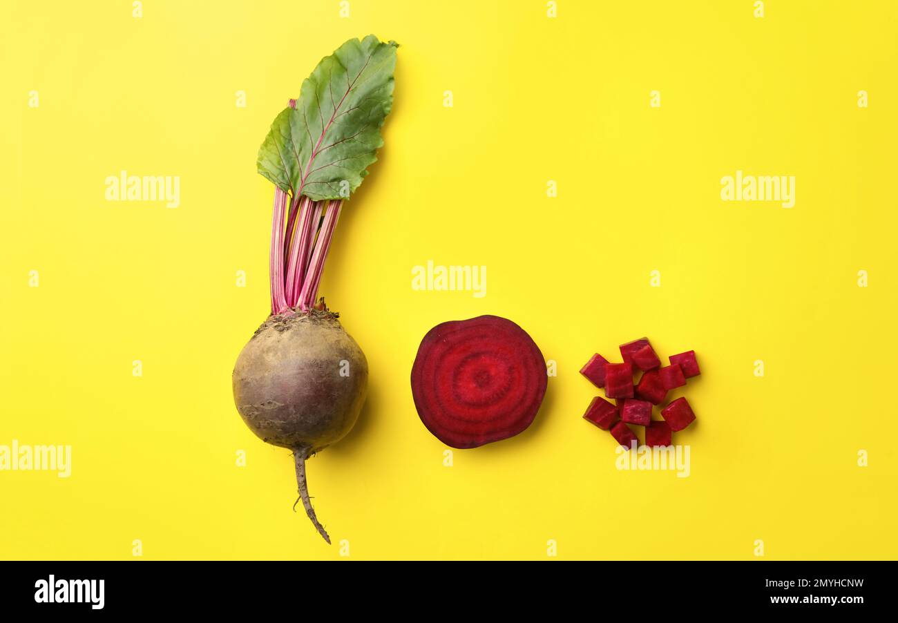 Whole and cut fresh red beets on yellow background, flat lay Stock Photo