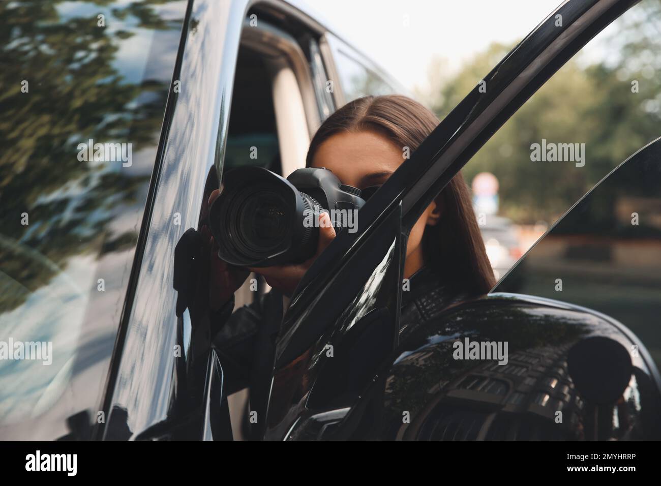 Private detective with camera spying near car outdoors Stock Photo