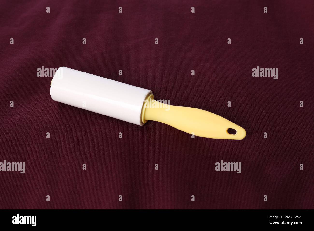 New lint roller with yellow handle on red fabric Stock Photo
