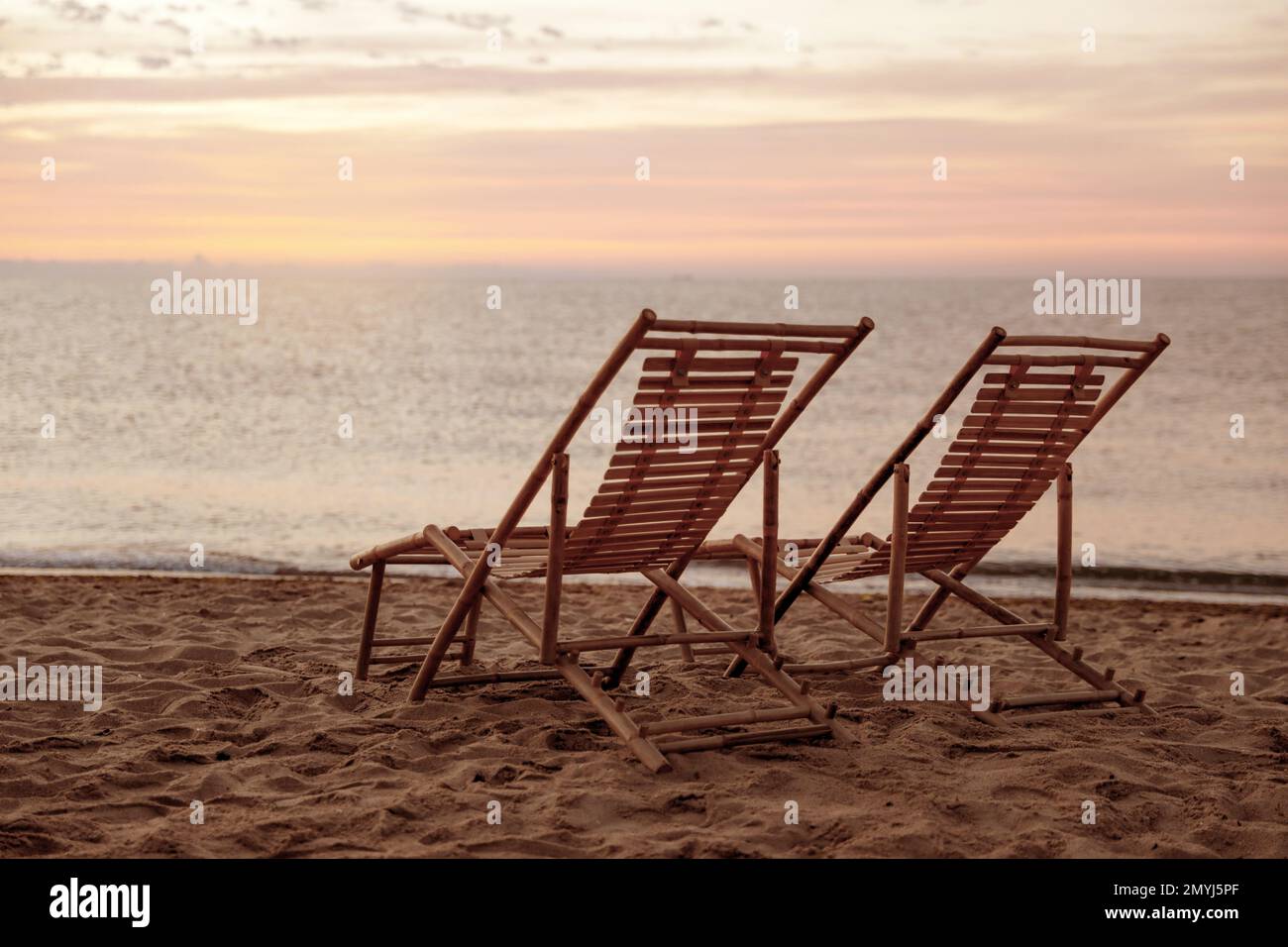 Wooden deck chairs on sandy beach at sunset. Summer vacation Stock ...