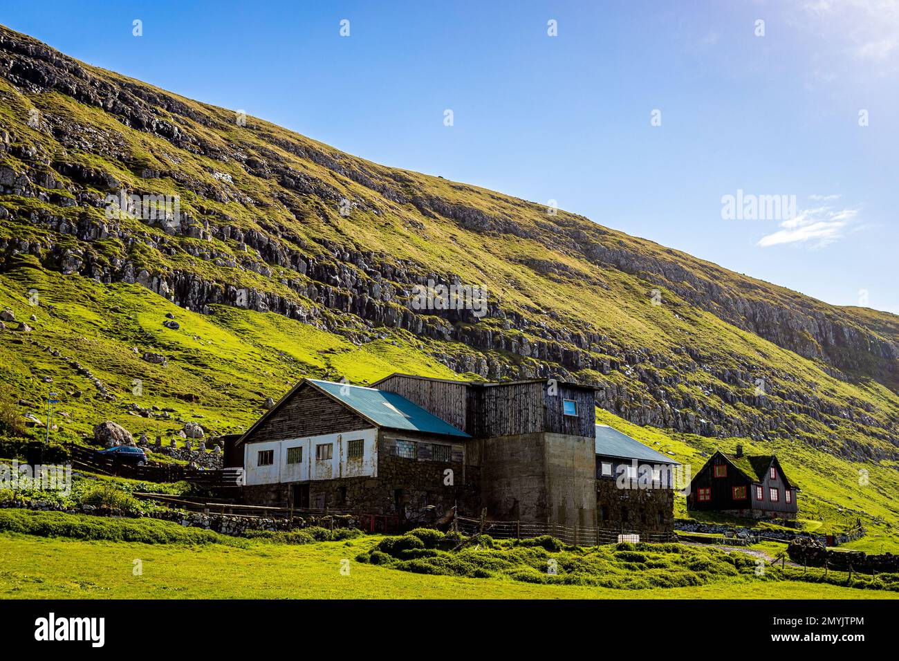 Old farm building and traditional house in Kirkjubøur, Streymoy, Faroe Islands on a sunny day Stock Photo