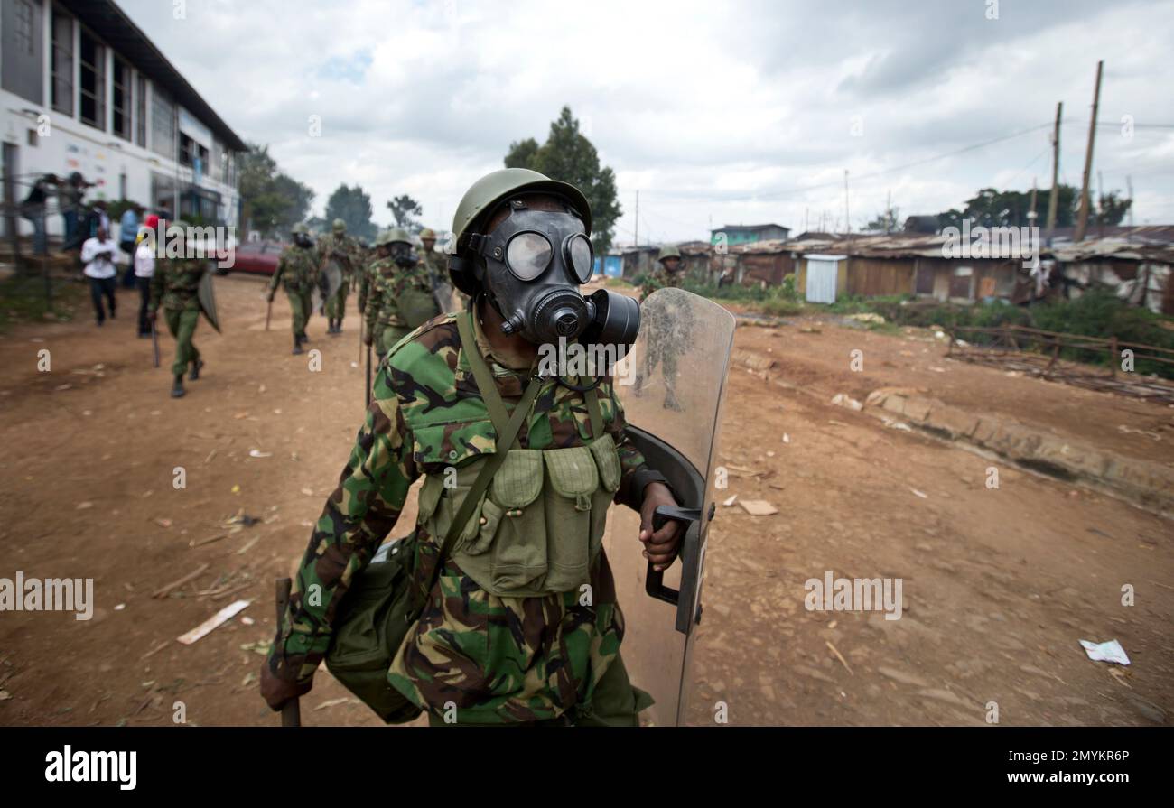 A Kenyan policeman wearing a gas mask chases protesters throwing rocks, in  the Kibera slum of Nairobi, Kenya, Monday, May 23, 2016. Kenya's police  shot, beat and tear gassed opposition demonstrators across
