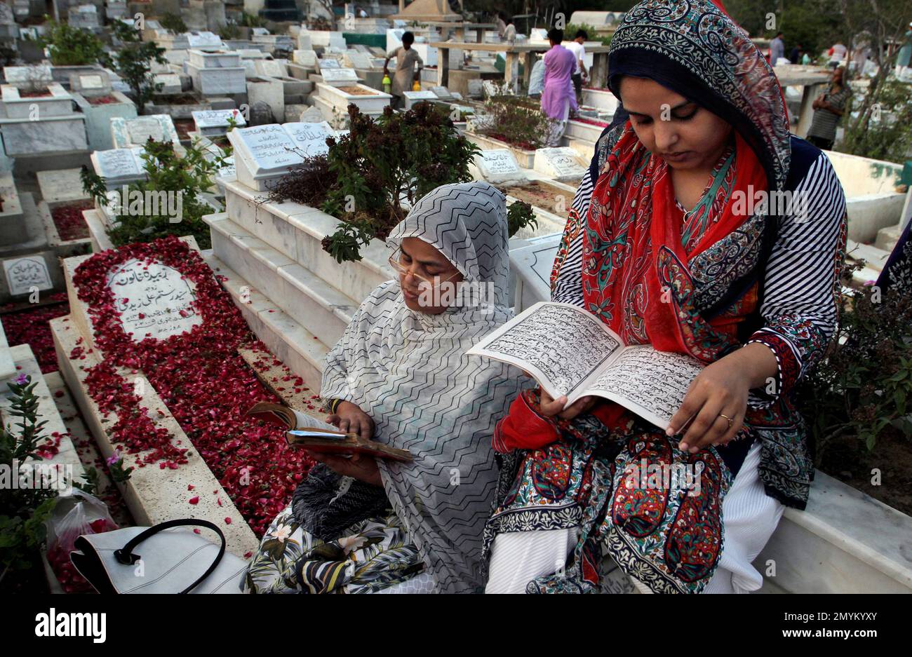 A Muslim family recite the Quran beside a graves of their relative to