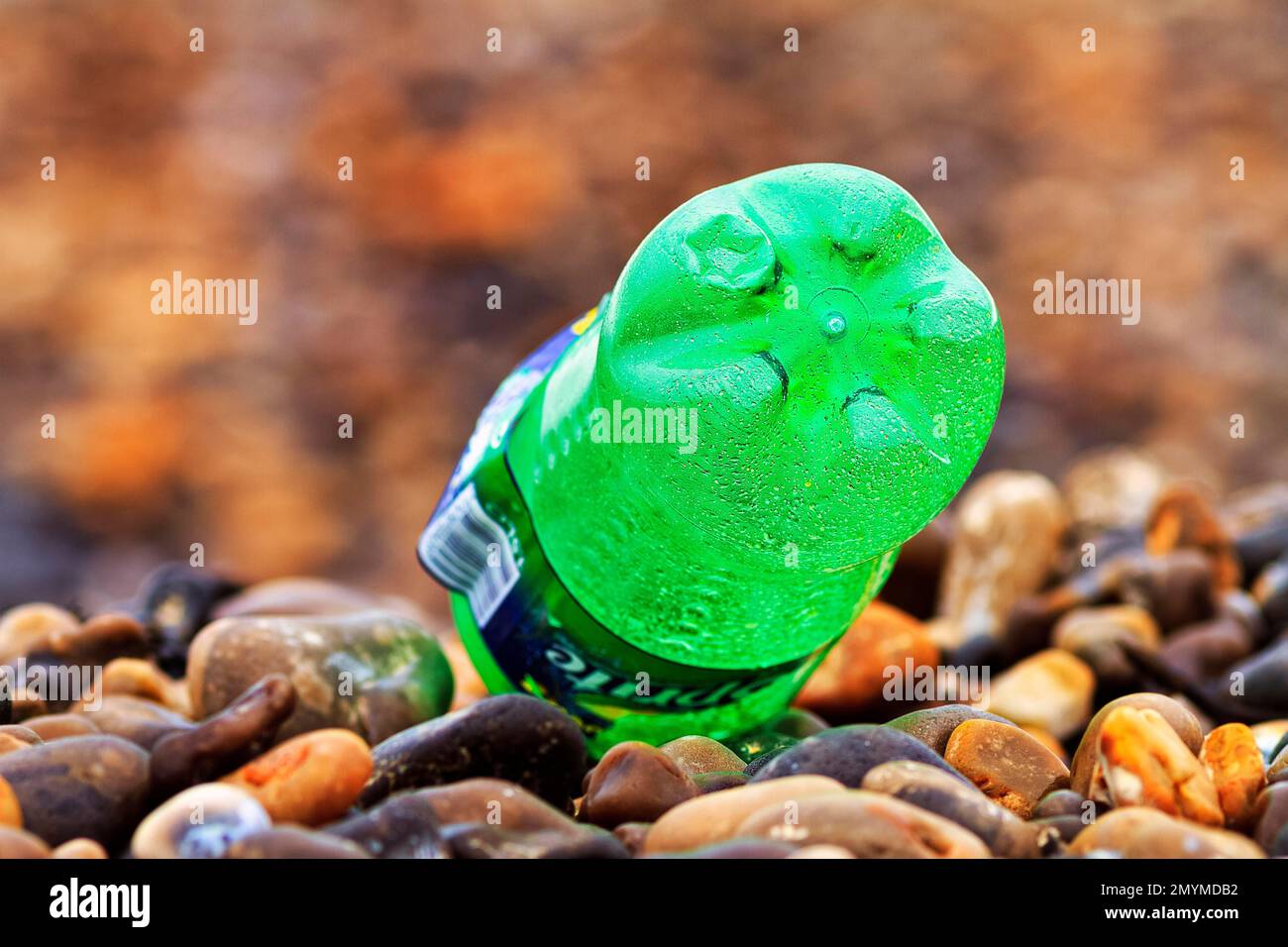 Green plastic bottle lying on pebble beach, plastic waste, Normandy, France, Europe Stock Photo