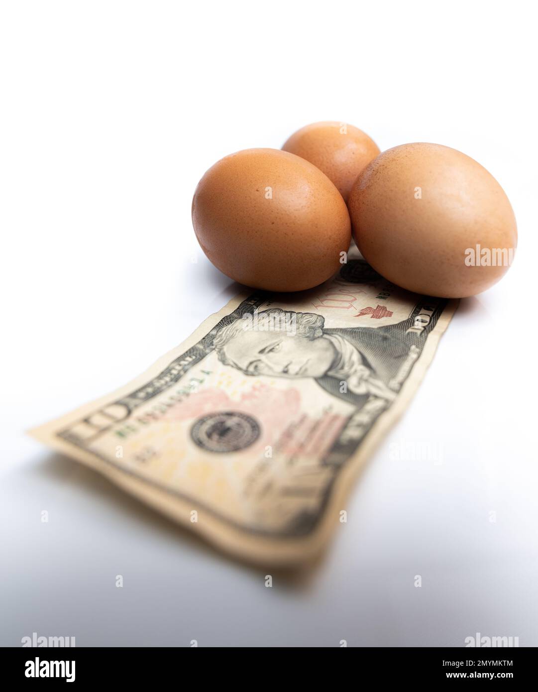 Fresh eggs on top of a 10 dollar US bill on a white background Stock