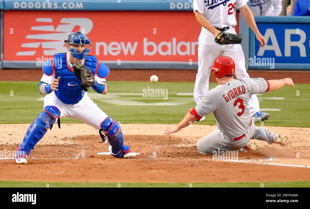 Los Angeles Dodgers catcher Yasmani Grandal, left, fails to catch the ball  thrown from right field, as St. Louis Cardinals' Jedd Gyorko (3) scores on  a sacrifice fly by Yadier Molina during