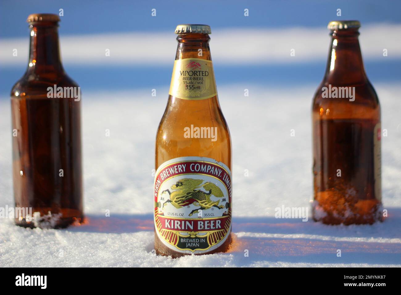 Three beer bottles in the snow, one old Japanese beer bottle in front. Stock Photo