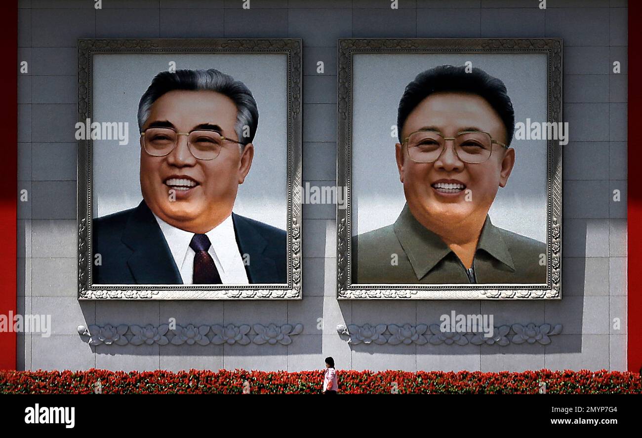 A woman is dwarfed as she walks past giant portraits of the late North ...