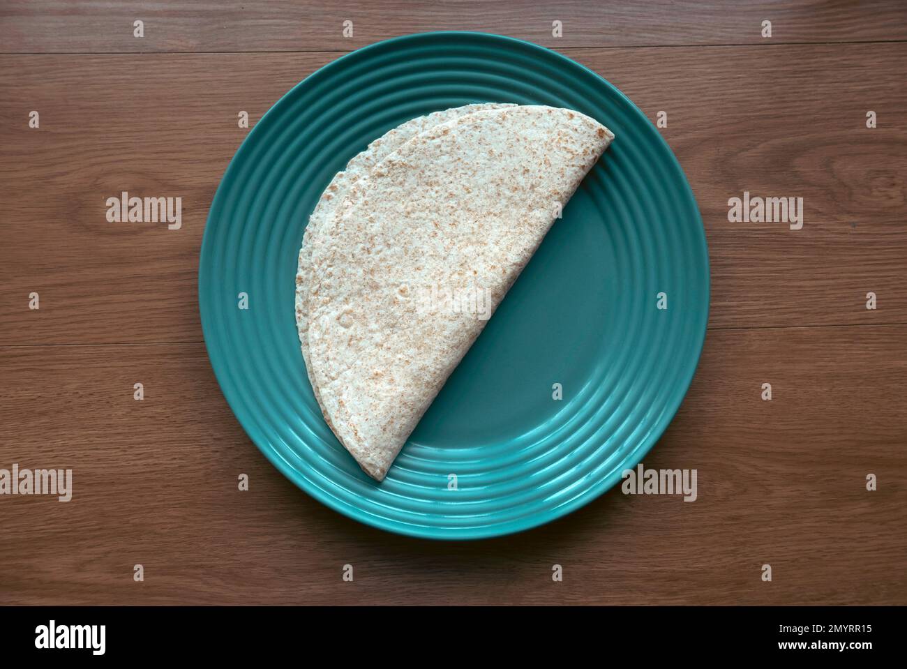 A folded wholegrain wrap on a green plate. Stock Photo