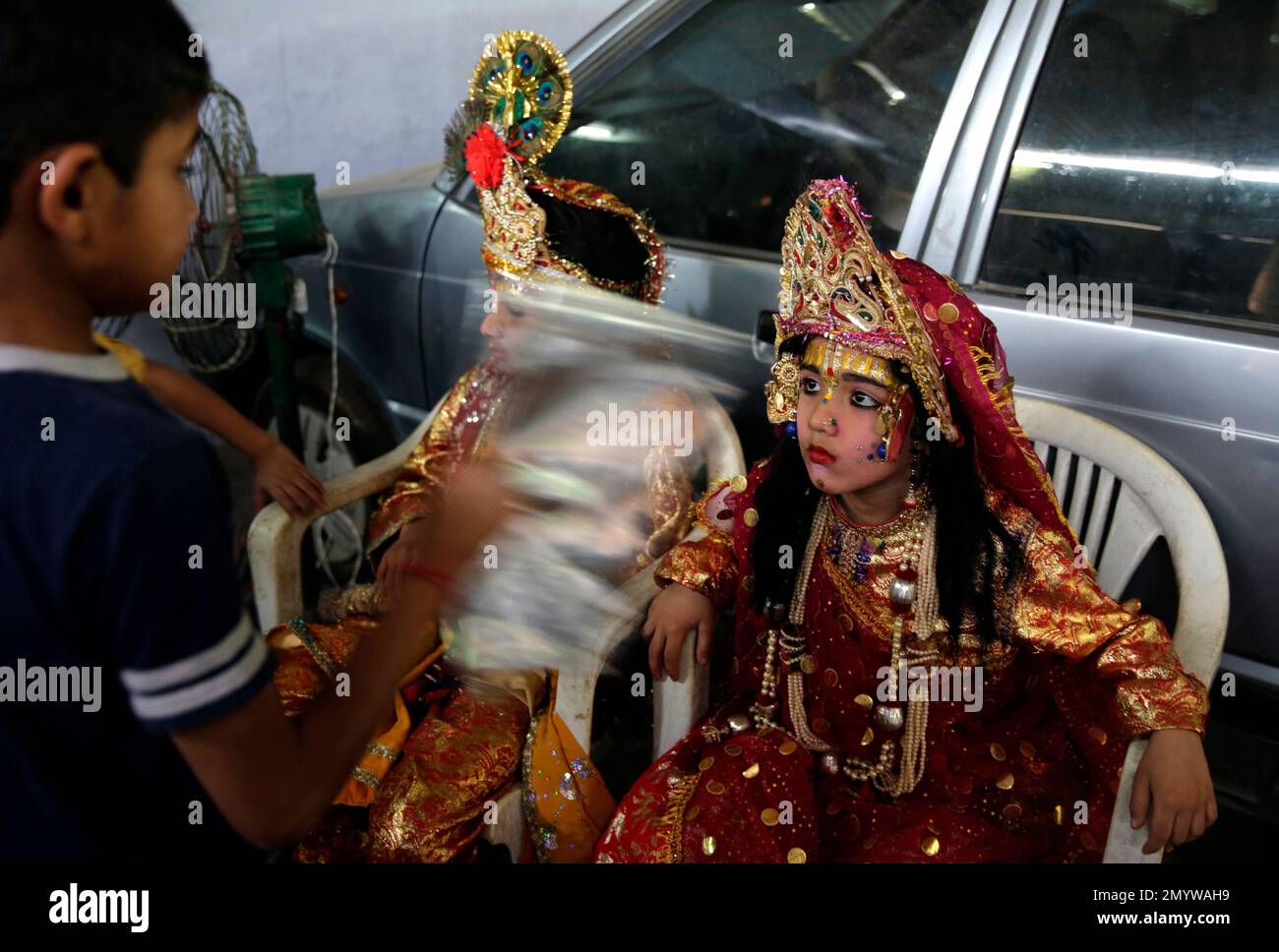 An Indian boy fans his friends dressed as Hindu God Ram and Sita, right ...