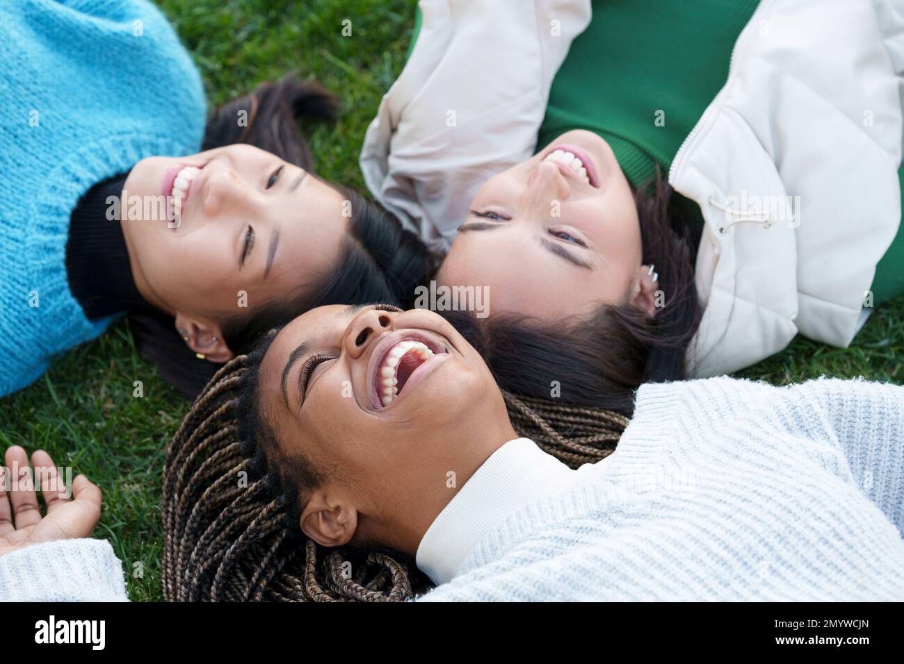Three happy friends lying on the grass Stock Photo