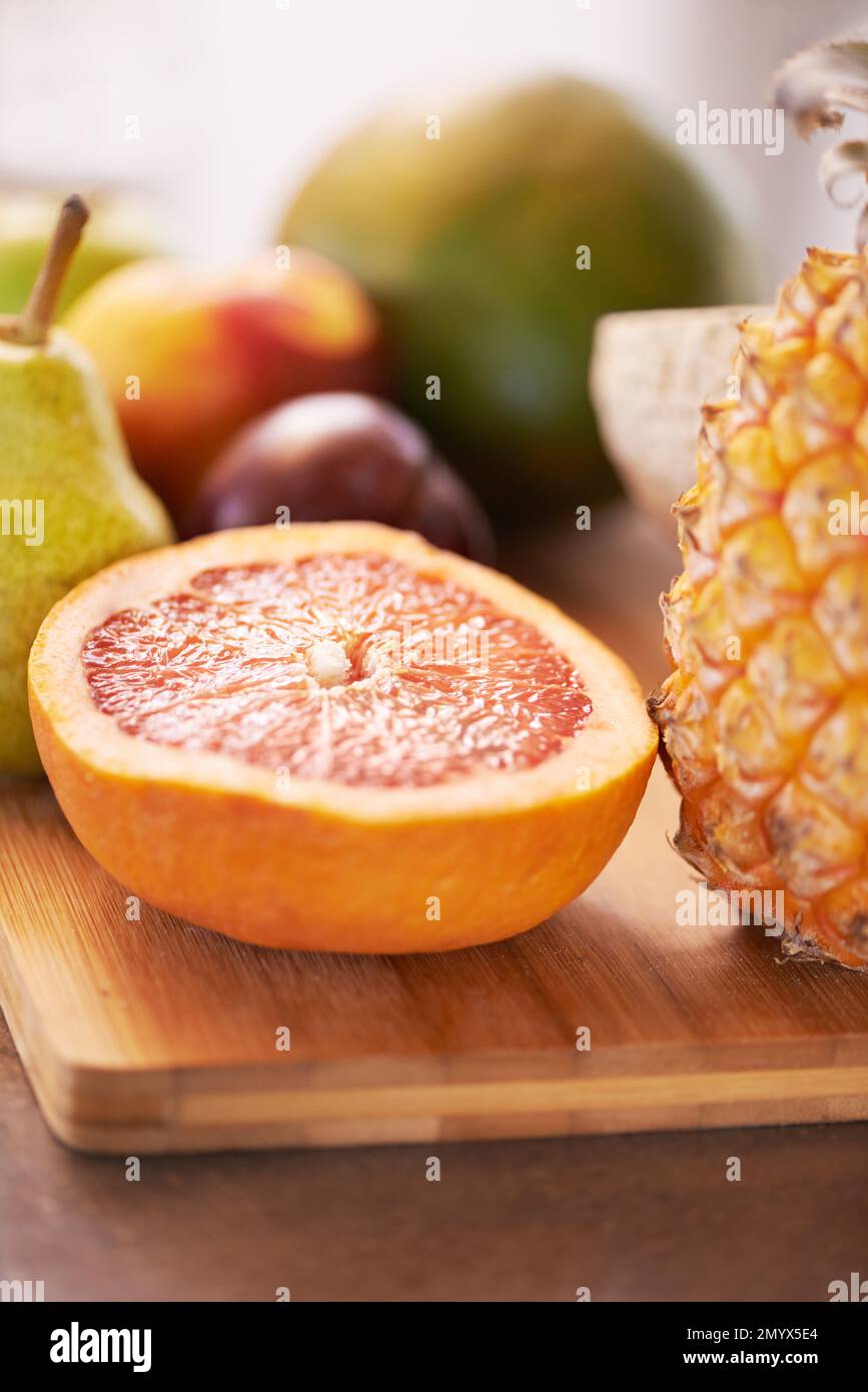 A healthy start to the day. A cropped shot of different fruits around a wooden chopping board. Stock Photo