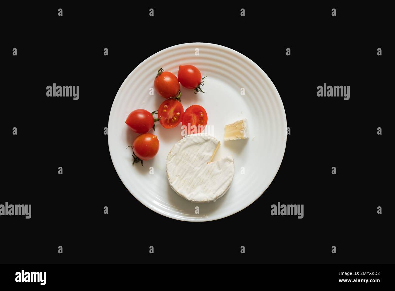piece of brie cheese and cherry tomatoes on a white plate Stock Photo