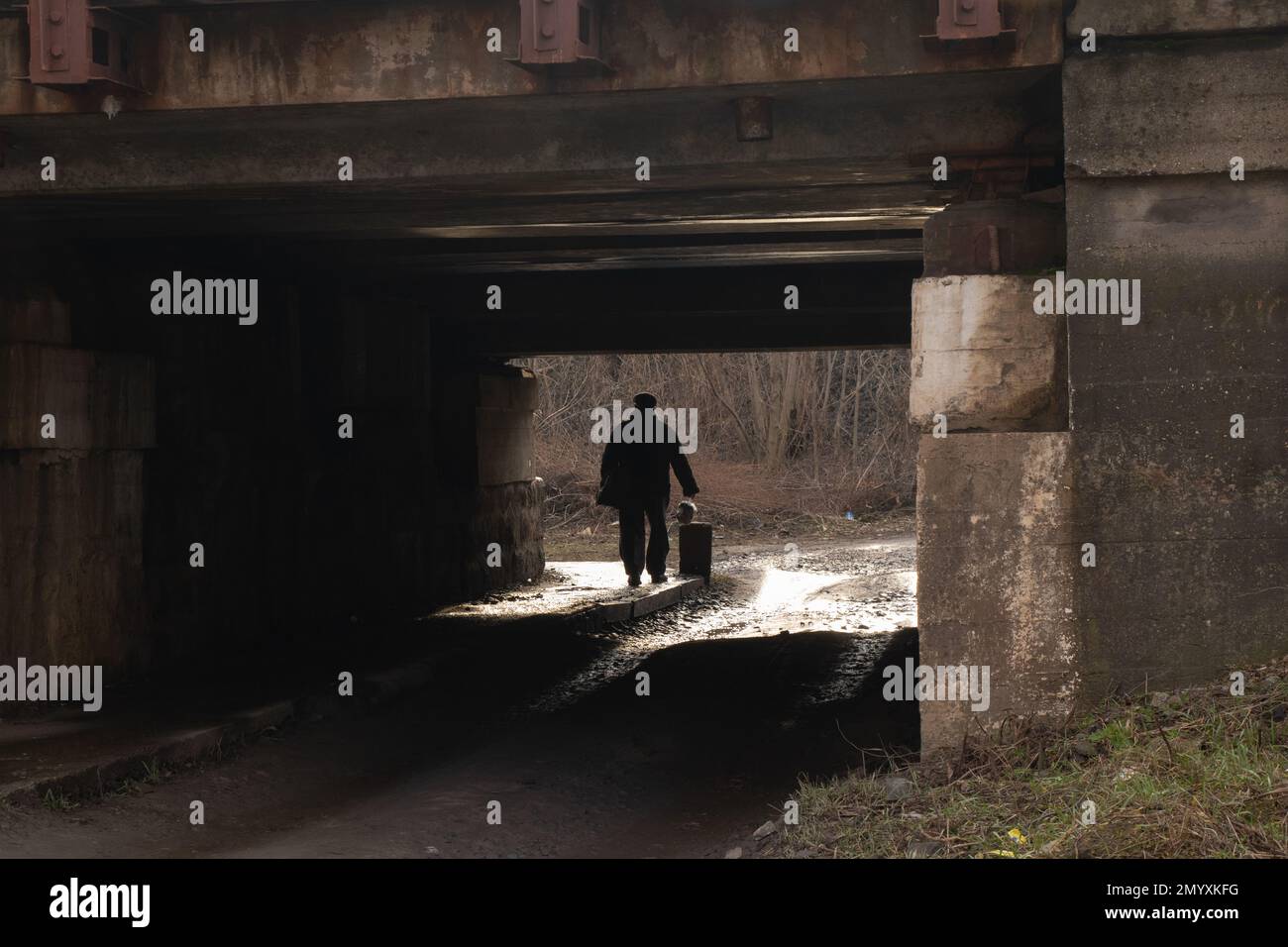 silhouette of a man passing under a railway bridge Stock Photo