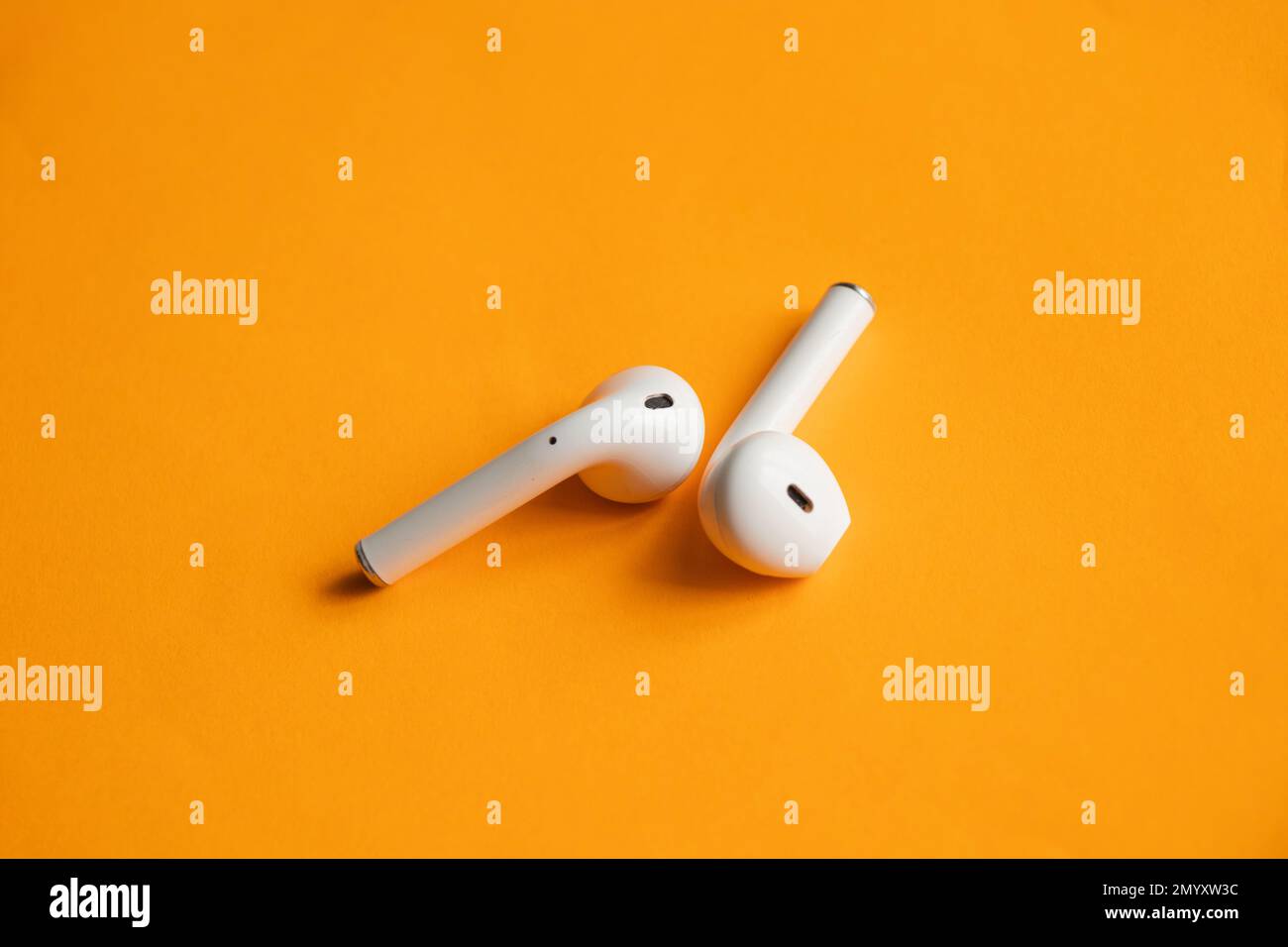 Wireless headphones lie on a light orange background Stock Photo