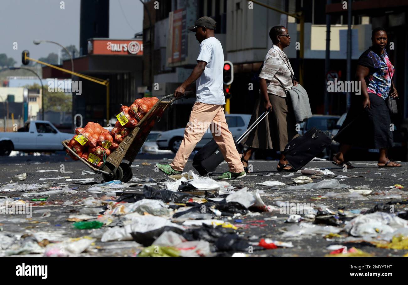 Pedestrians Cross An Intersection Littered With Uncollected Refuse In pedestrians-cross-an-intersection-littered-with-uncollected-refuse-in