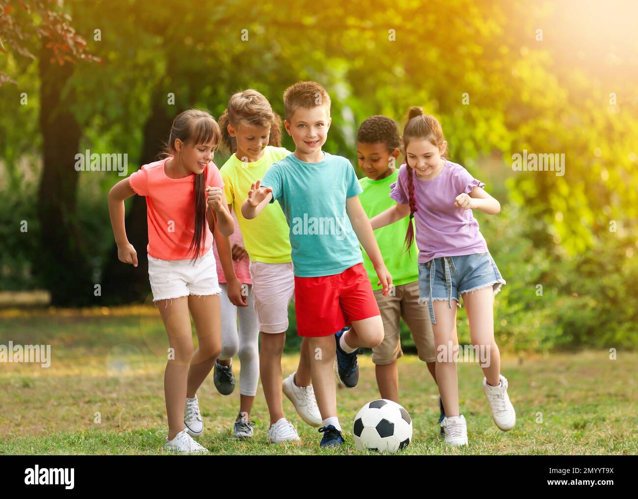 School holidays. Group of happy children playing football outdoors