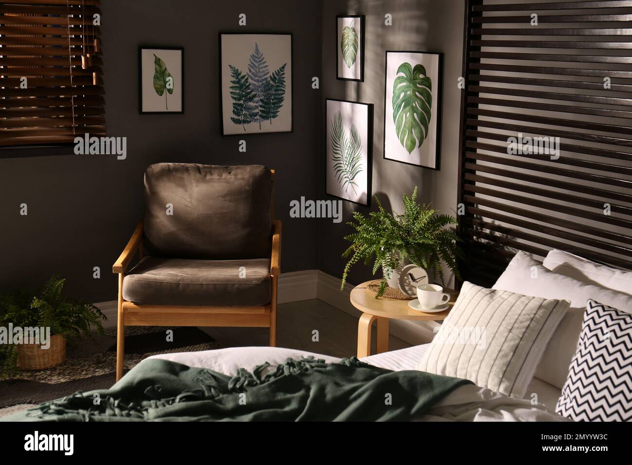 Comfortable bedroom with armchair and pictures on wall. Interior design
