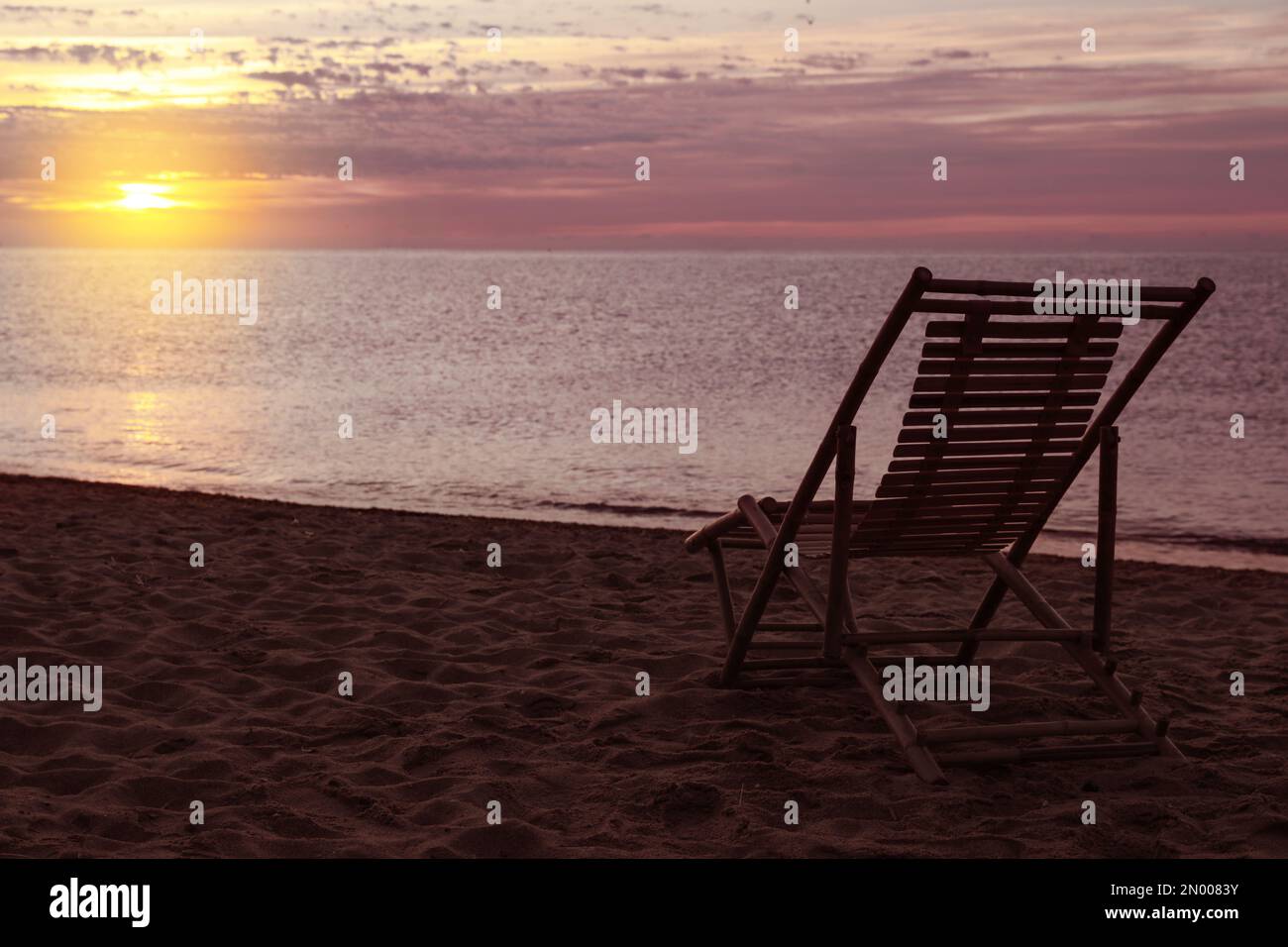 Wooden deck chair on sandy beach at sunset. Summer vacation Stock Photo ...