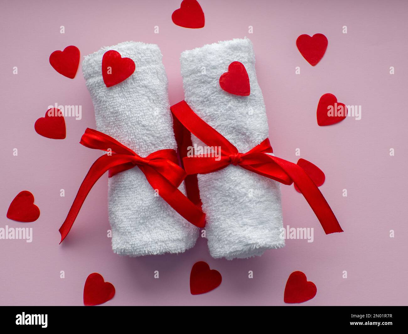 Flat lay with tiny heartshaped papers, two white towels and space for