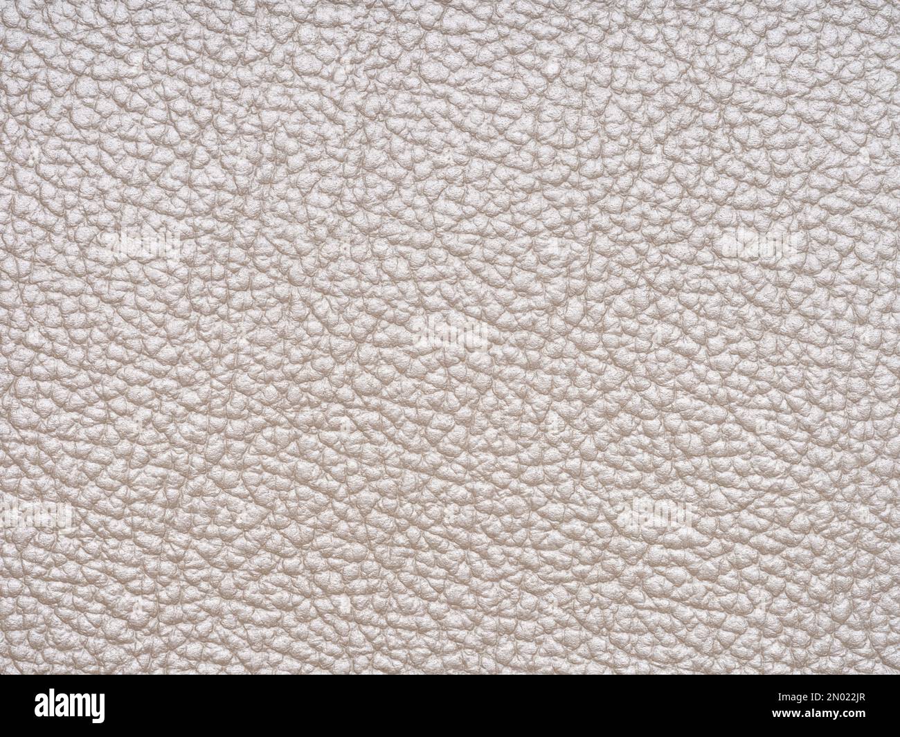 Beige leather texture sample. Genuine leather material closeup in light, soft tone. Background