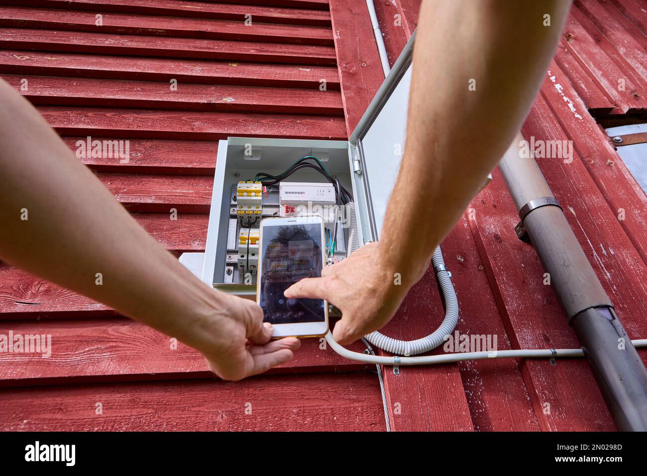 Taking readings from electric meter, homeowner photographs display of external electricity meter. Stock Photo