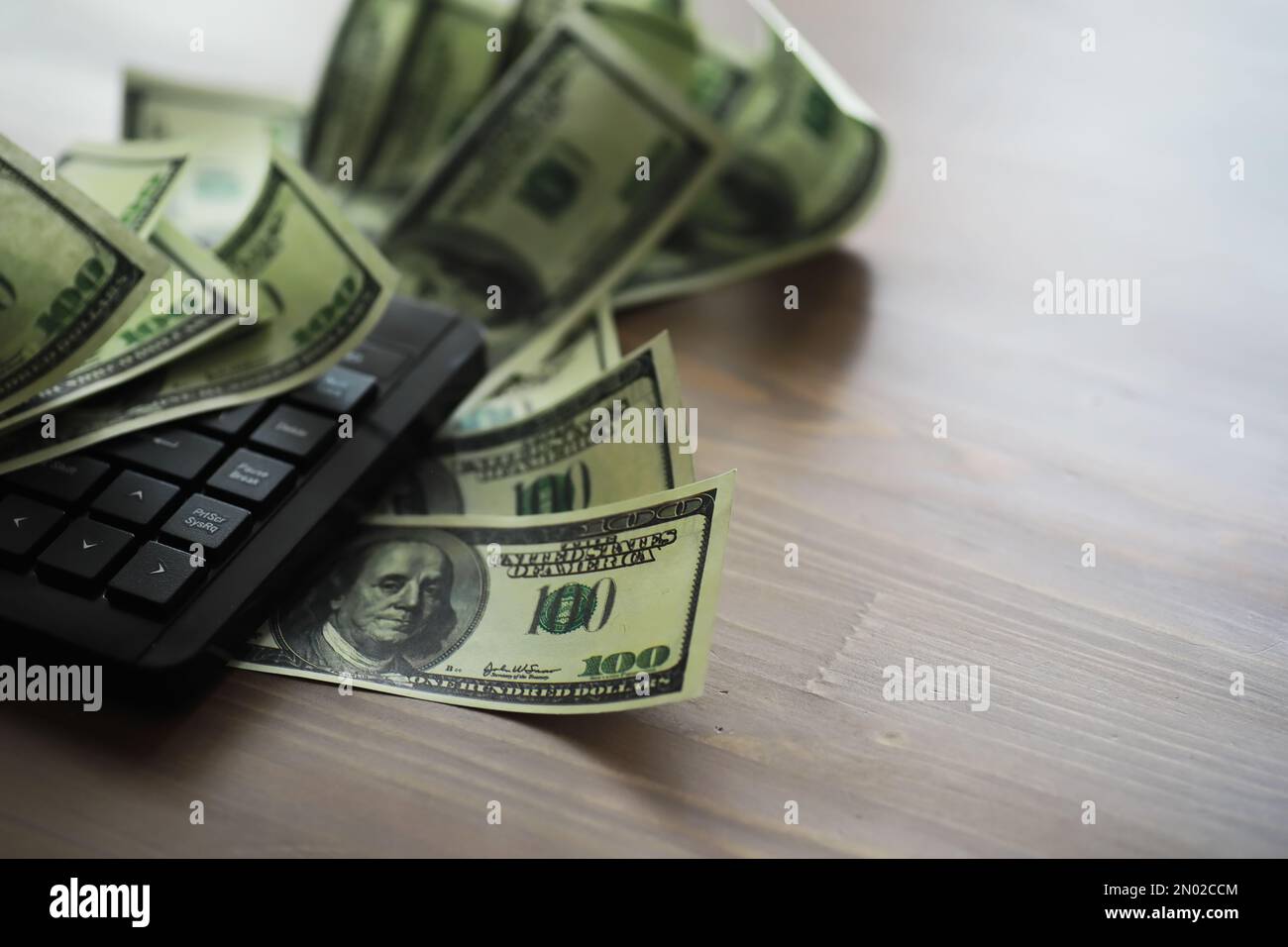 Computer keyboard and a scattering of 100 dollar bills on the table ...