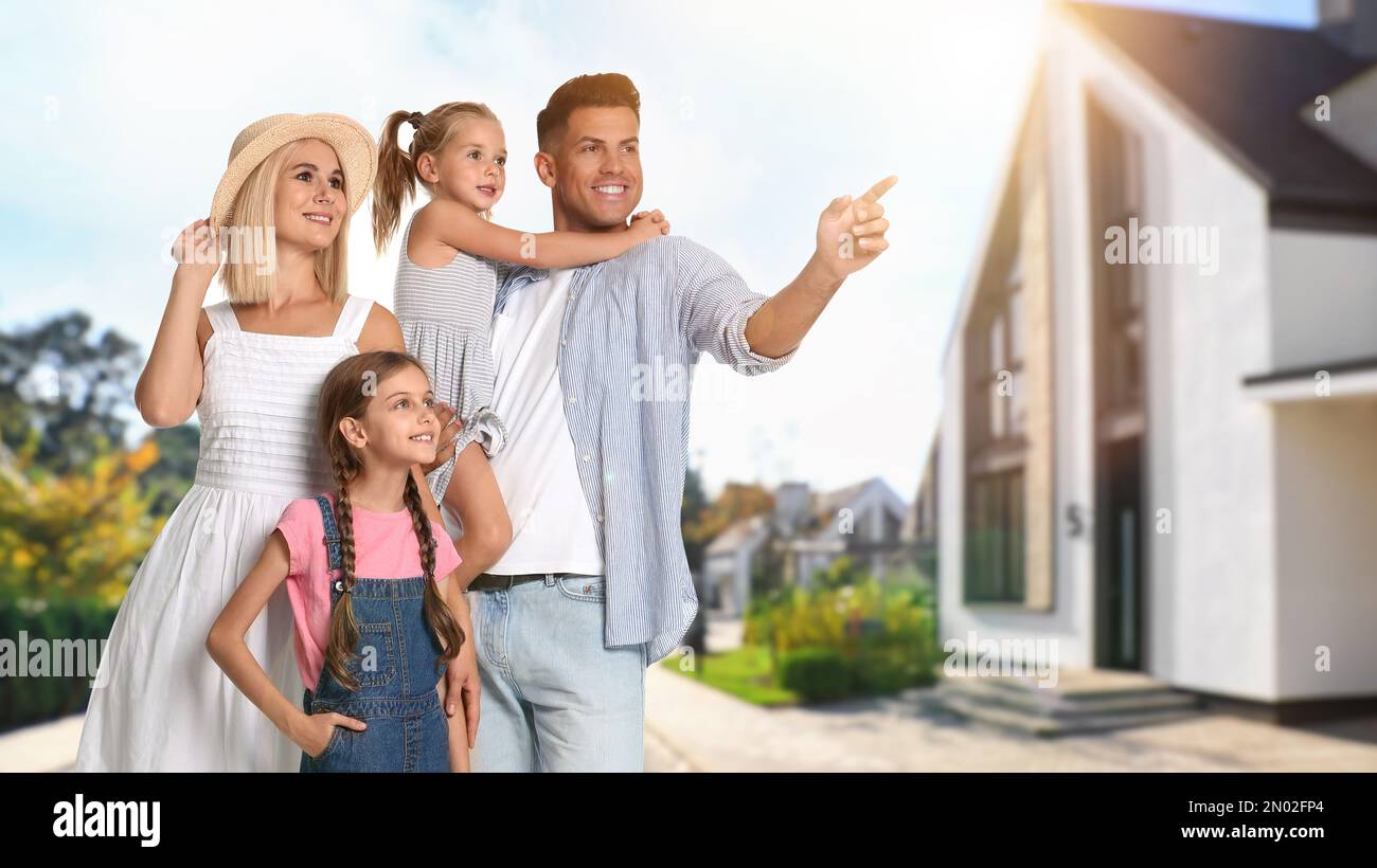 Happy family standing in front of their house on sunny day Stock Photo