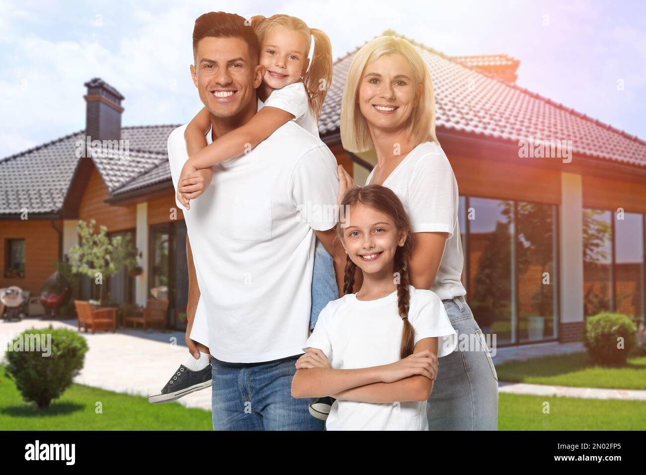 Happy family standing in front of their house on sunny day Stock Photo ...