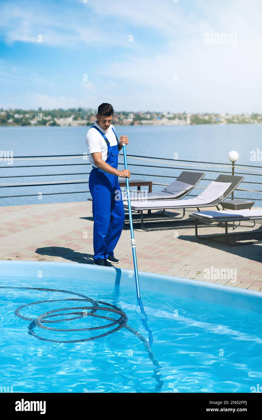 Worker cleaning outdoor swimming pool with underwater vacuum Stock