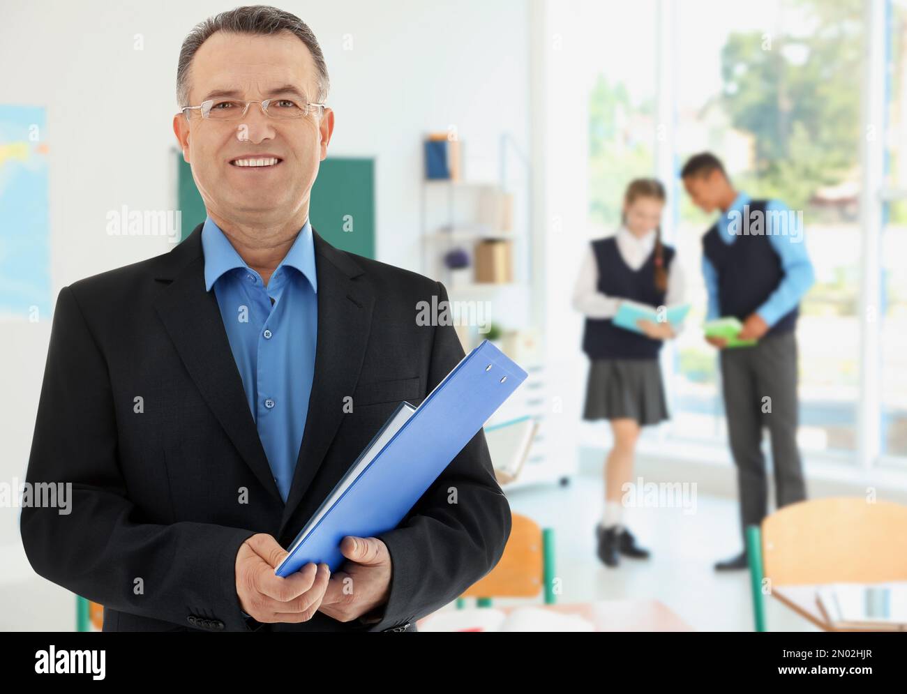 Happy school teacher in classroom with students Stock Photo - Alamy
